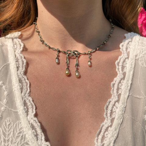 Pearl dropper necklace worn on the neck with a white lace neckline