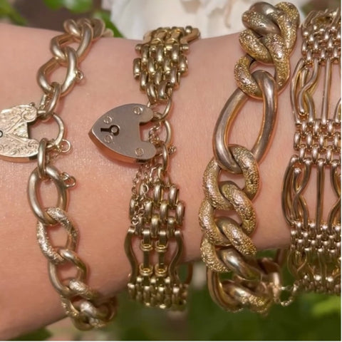 Four gold chain bracelets with heart padlocks worn on the wrist