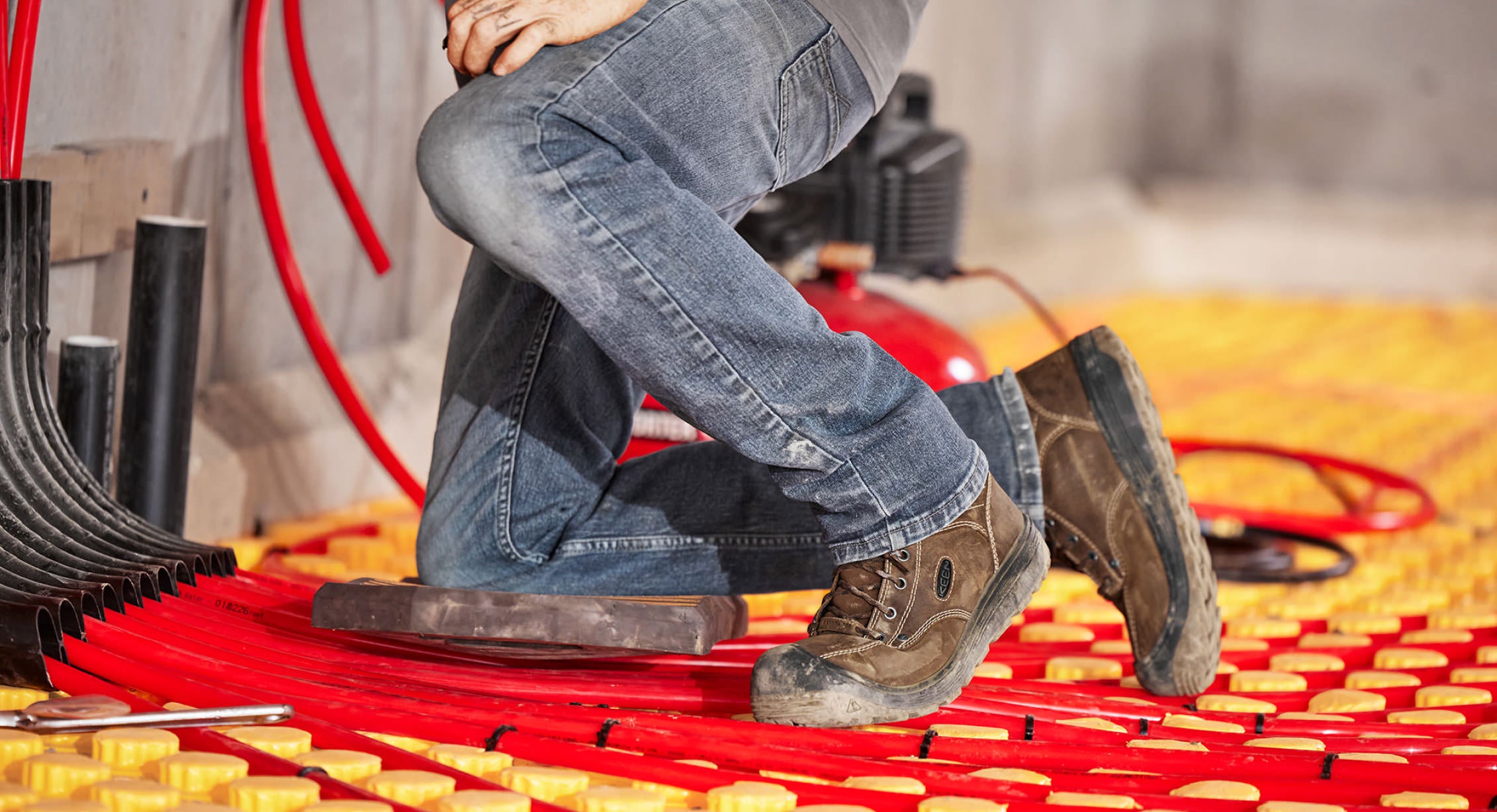 Worker kneeling on work surface laying heating coils