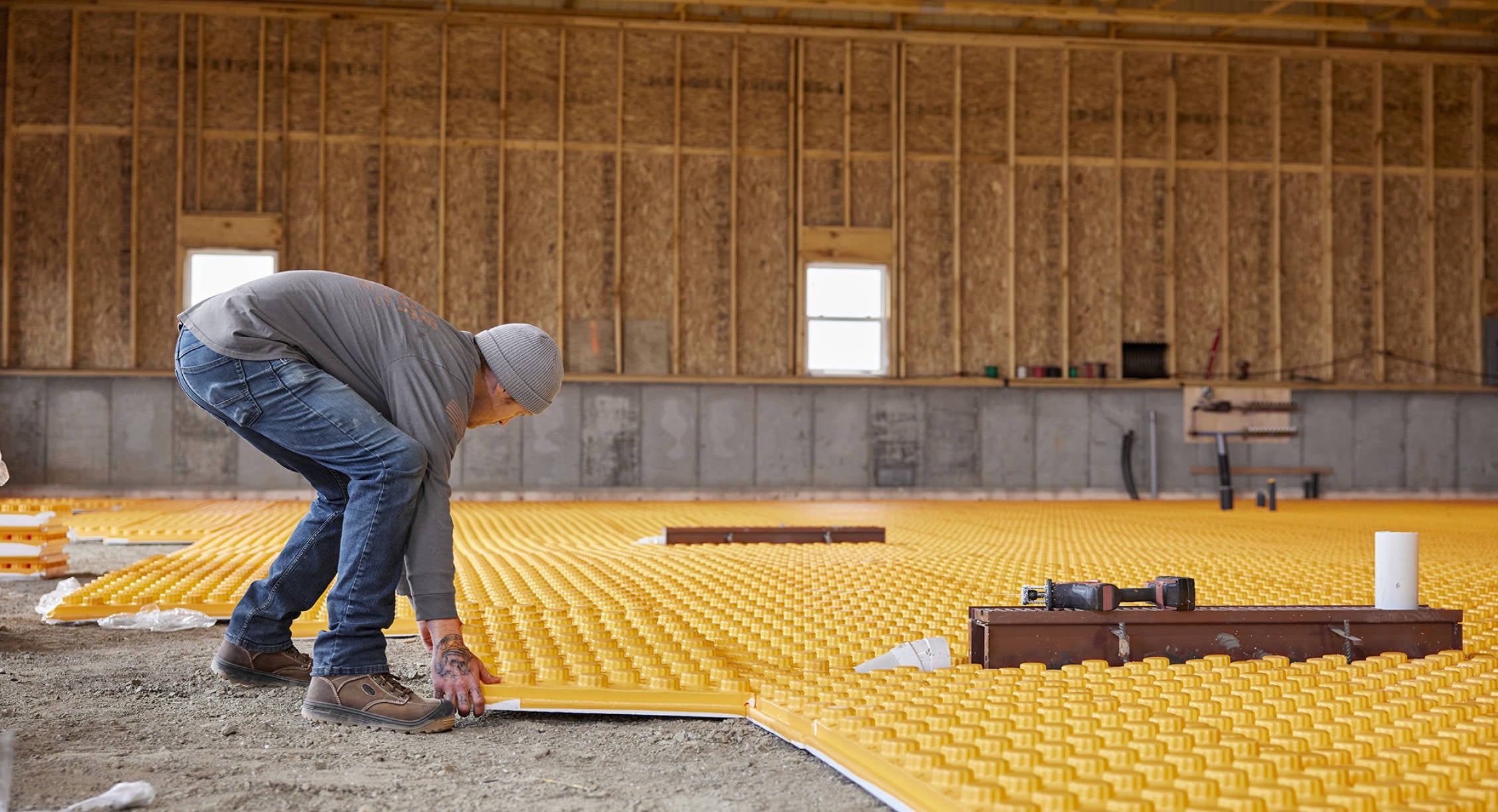 Construction worker laying flooring insulation.