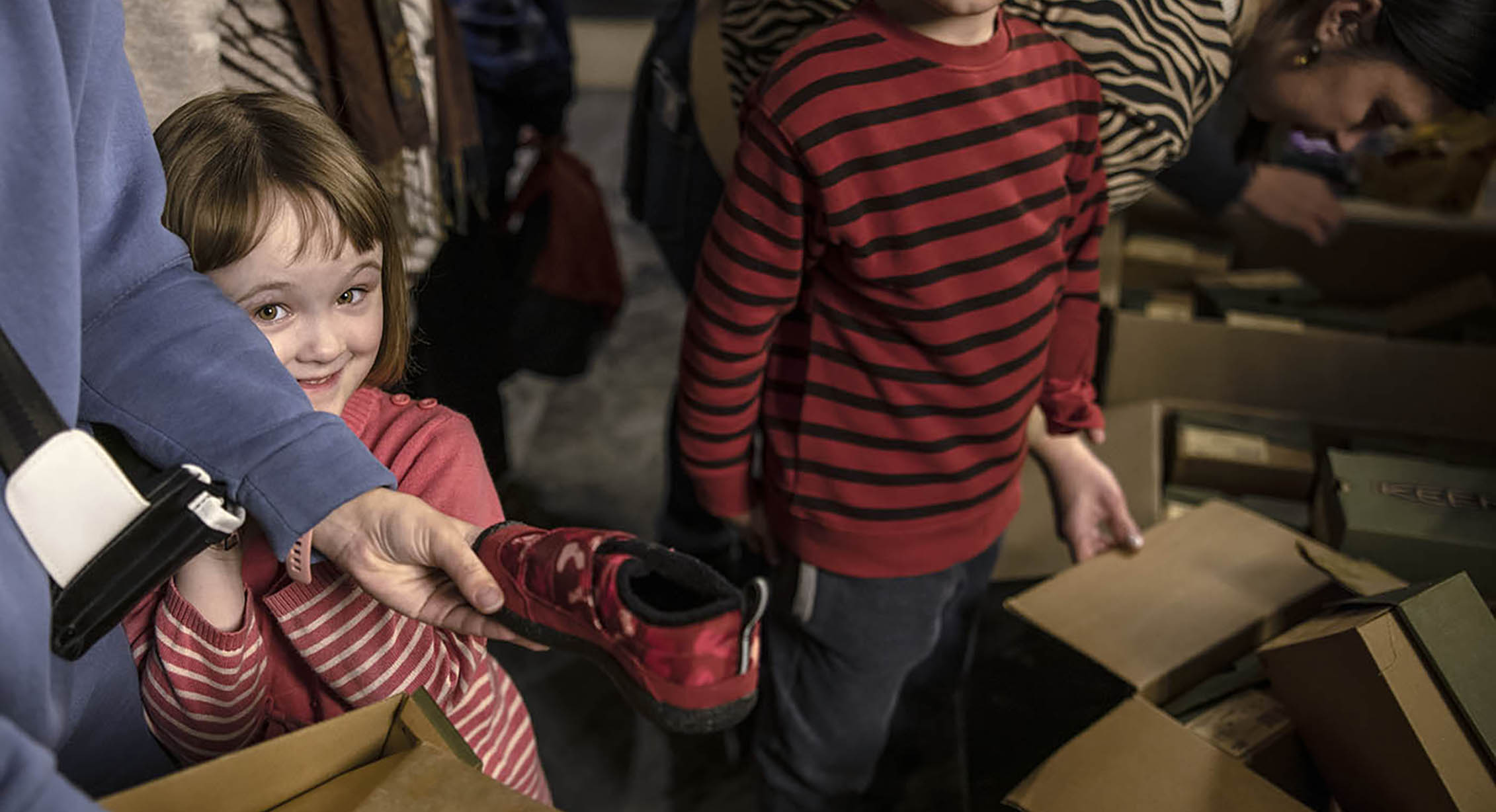 A Ukrainian refugee child picking out new shoes from KEEN