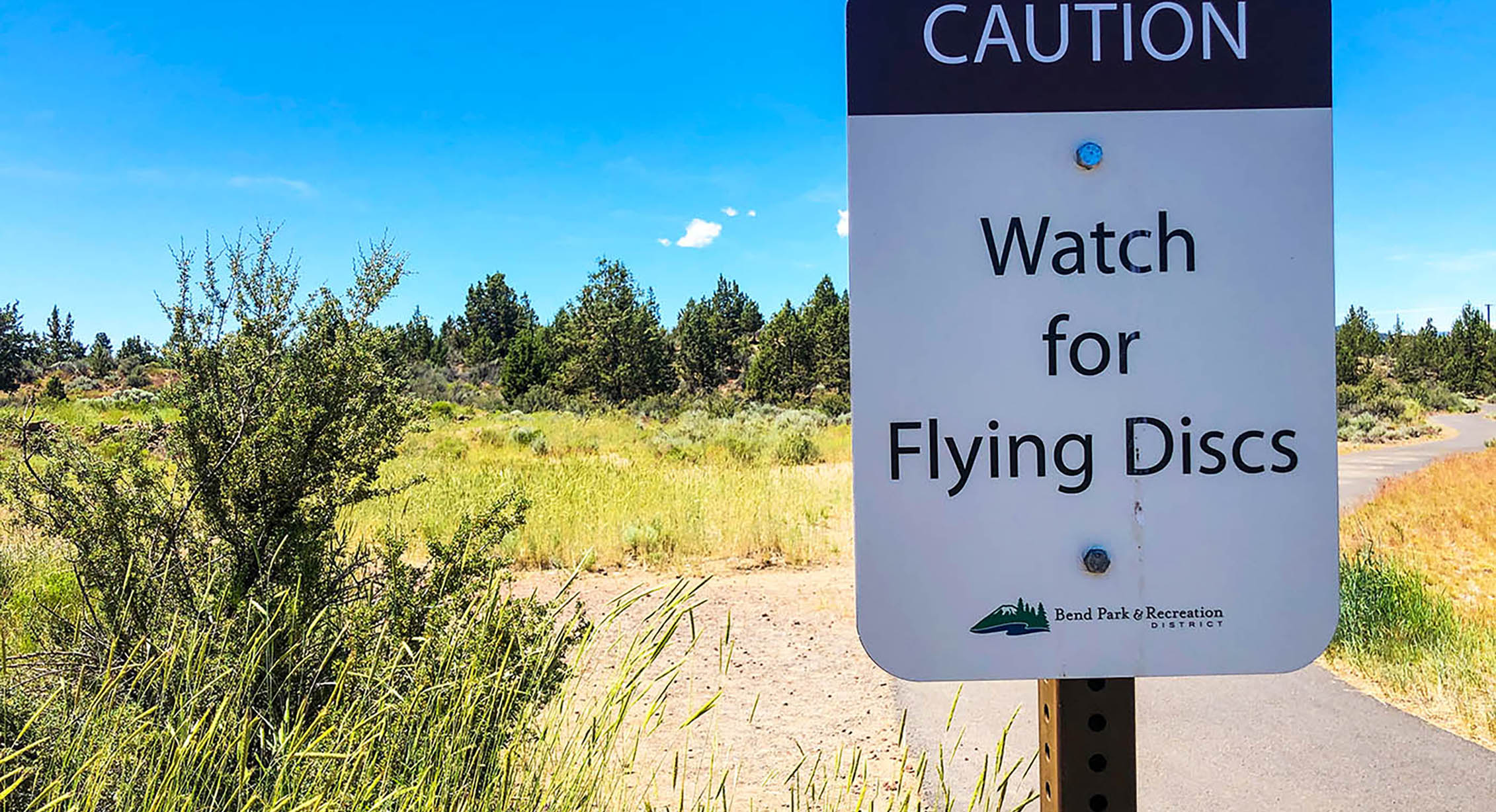 a warning sign near a disc golf course