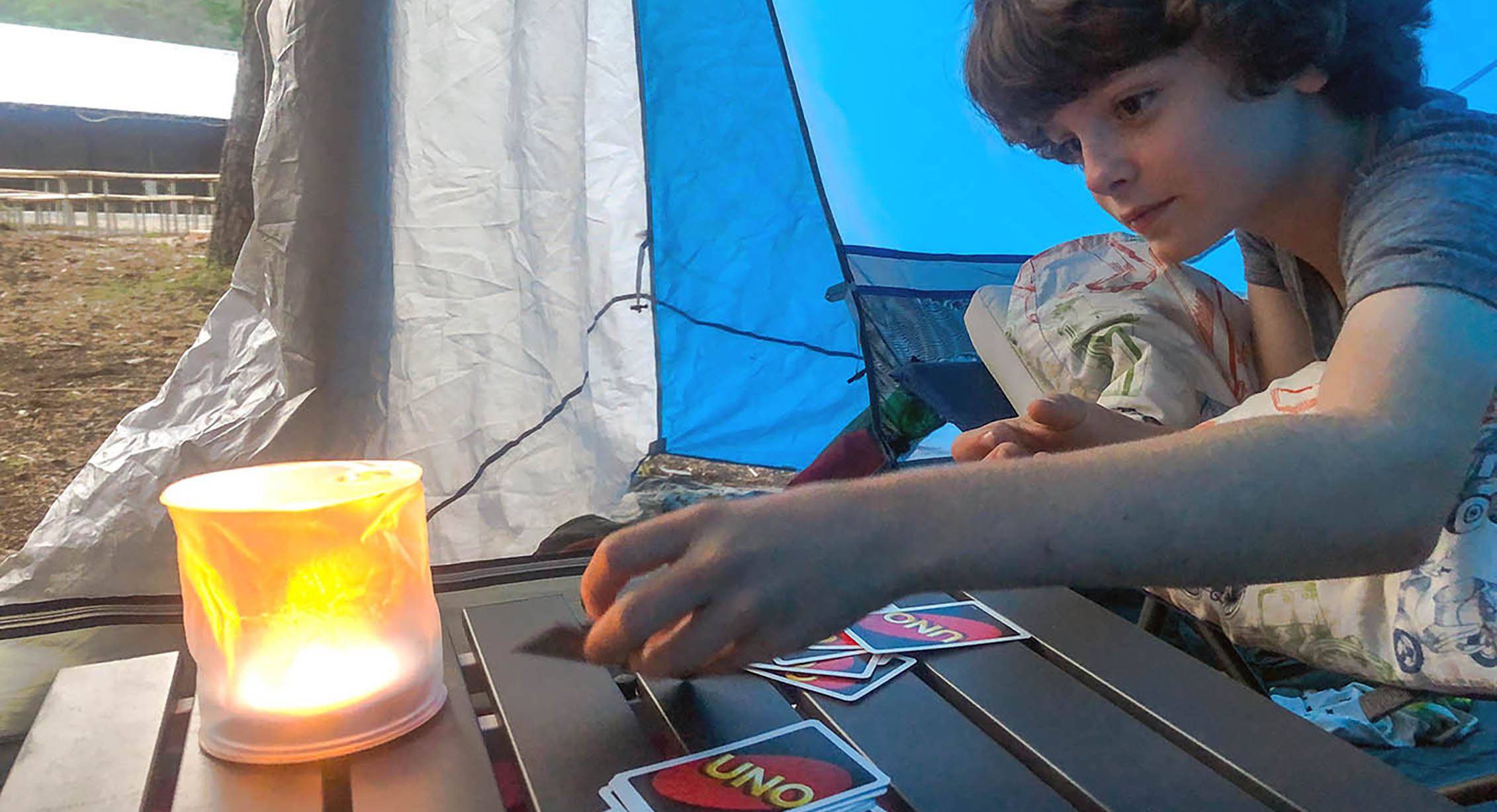 A child playing Uno while camping