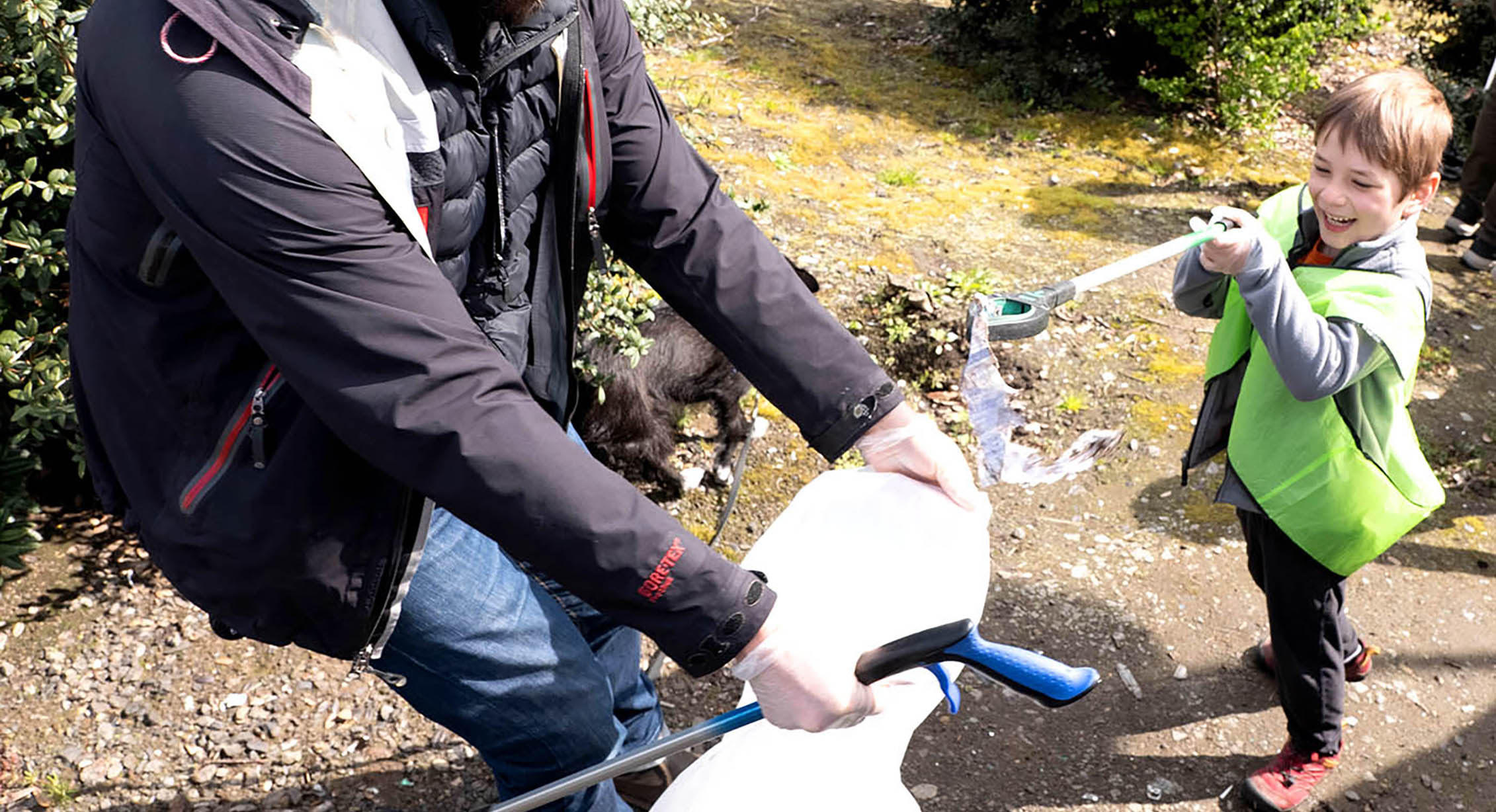 A kid picking up litter with his dad