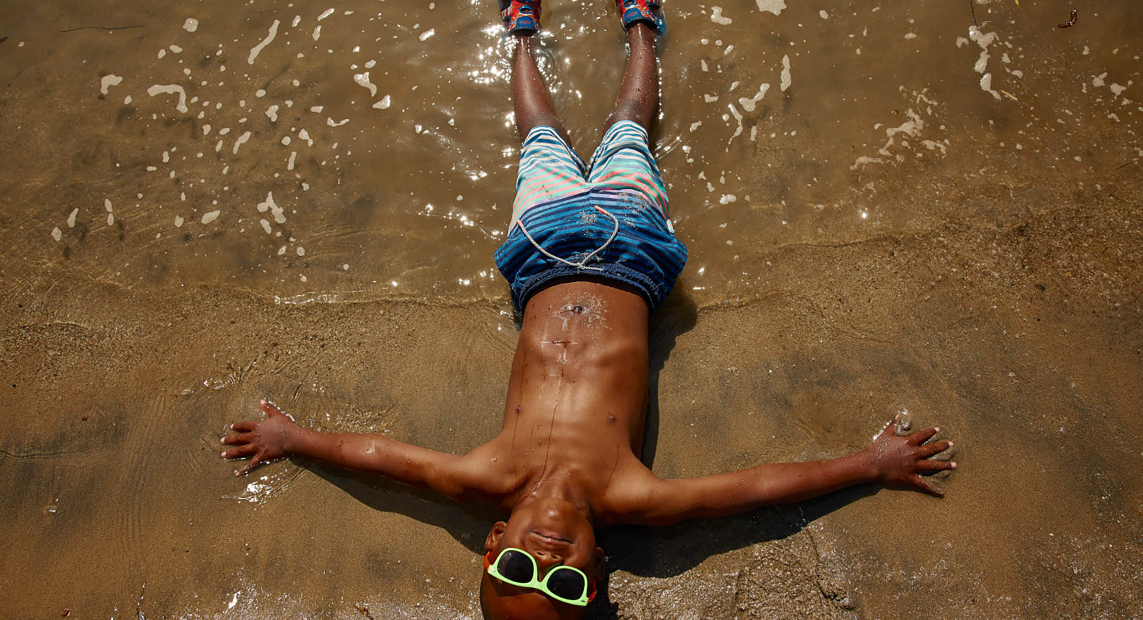 un enfant allongé sur le sable à la plage