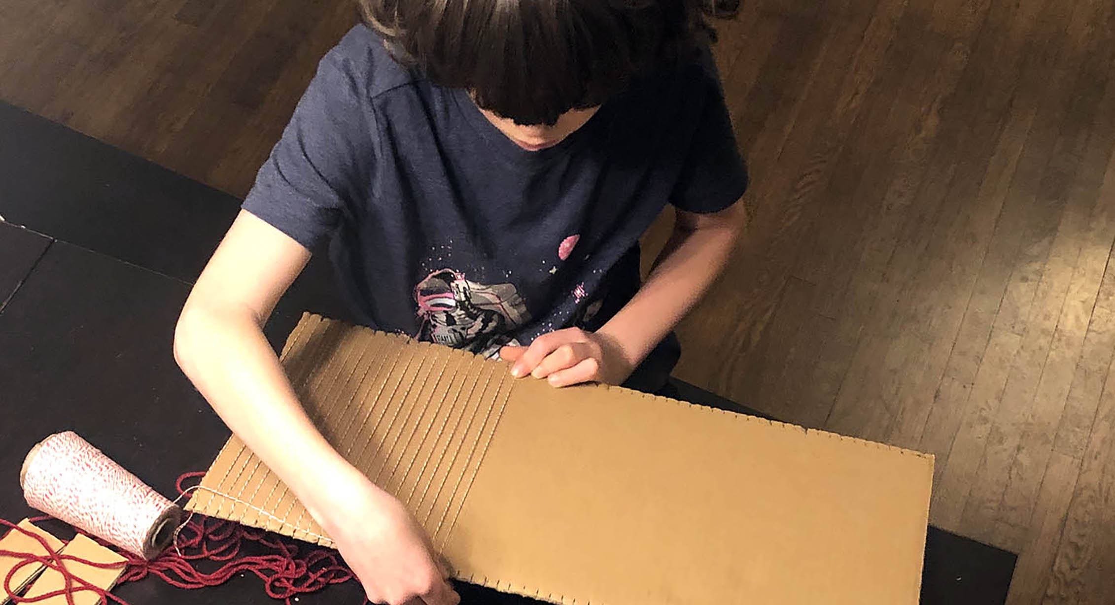 A child using a cardboard loom