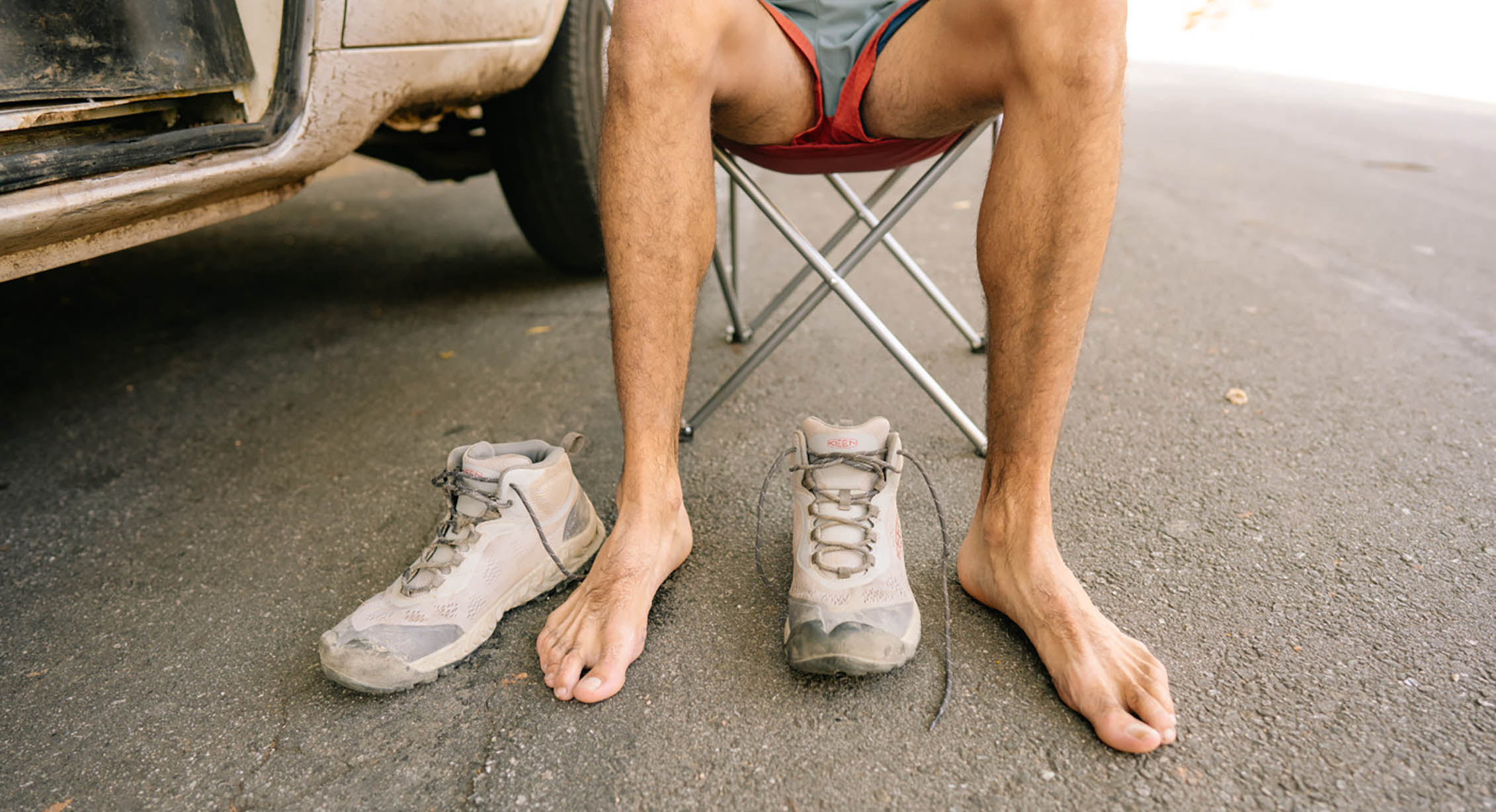 une paire de pieds nus se détend à côté d'une paire de chaussures de randonnée NXIS