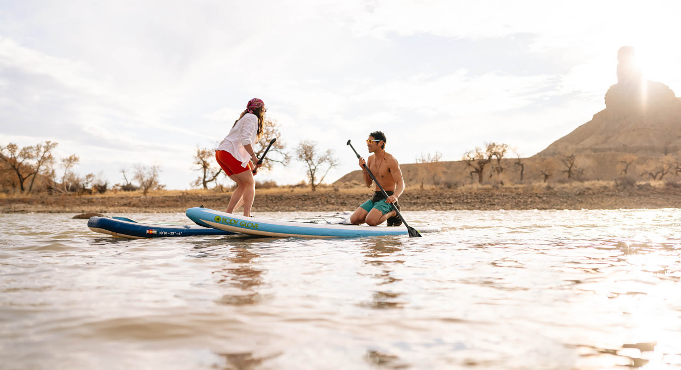 a couple paddleboarding on a river