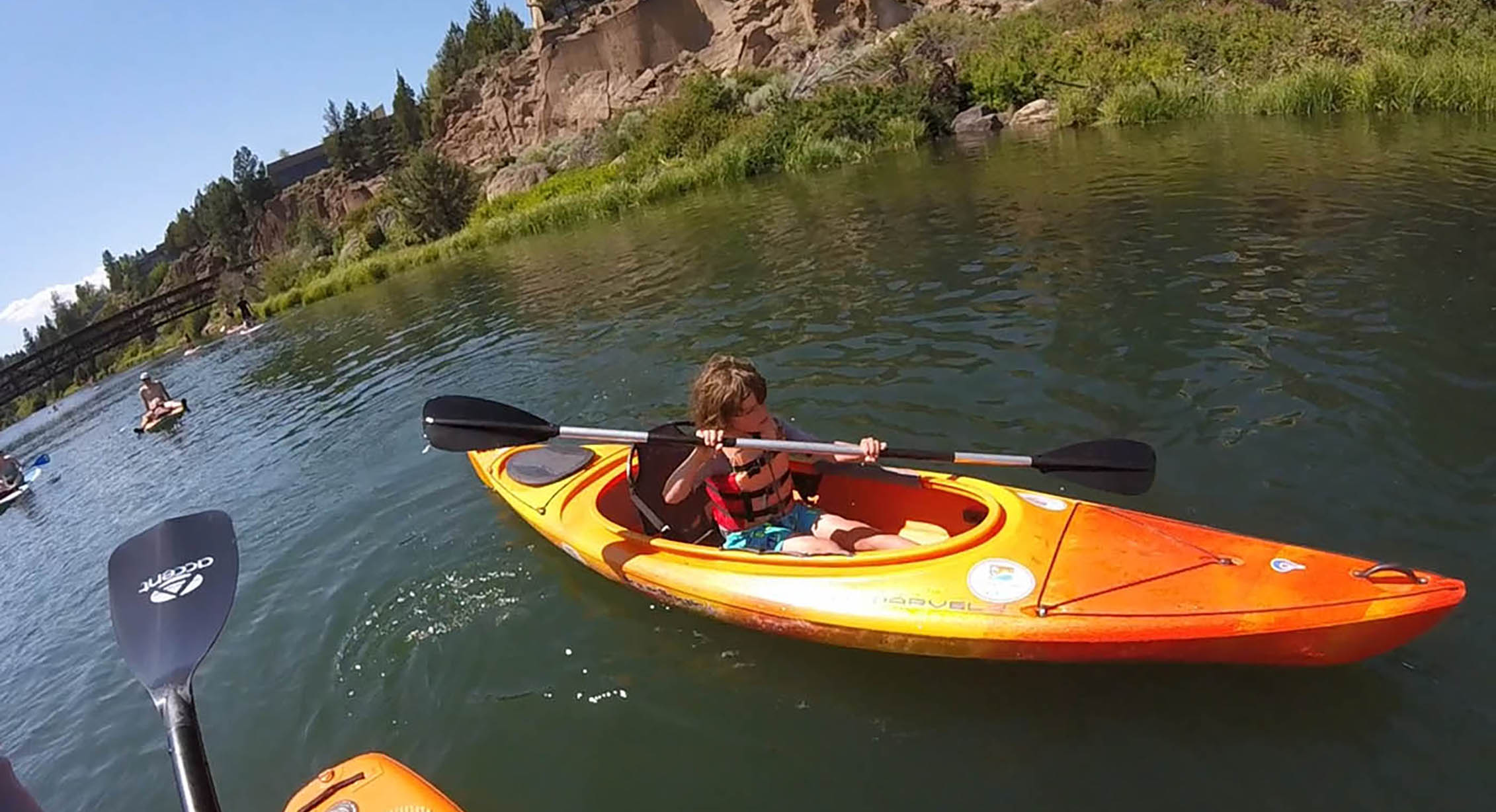 a boy kayaks on a river
