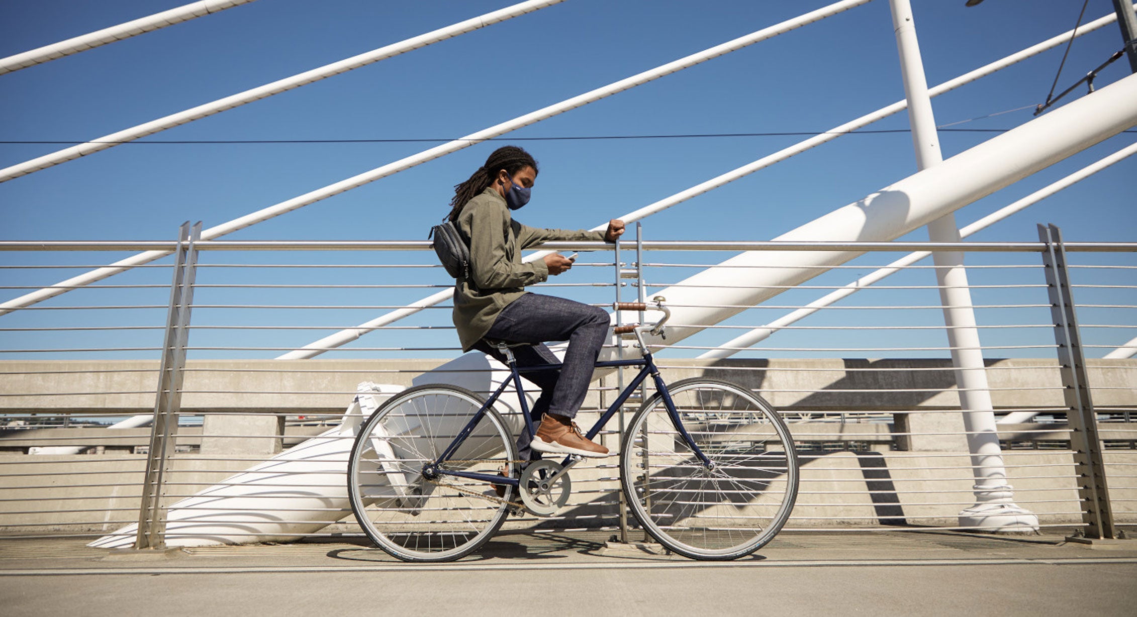 a person sits on their bike on a city bridge checking their phone