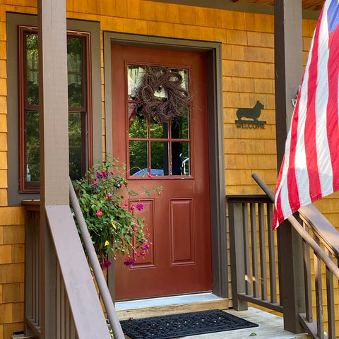Corgi welcome sign mounted next to a door on a front porch