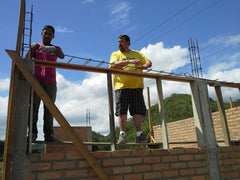 Jason standing on top of a wall of bricks,, tying rebar for a window frame