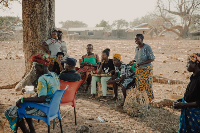 smiling weavers sit outside in a group