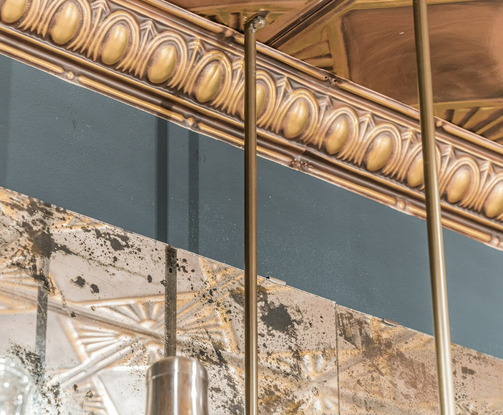 Ceiling finished with tin crown moldings with ornate pattern and gold color.