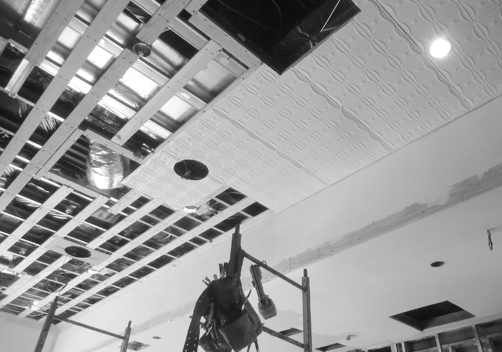 Furring strips on a ceiling and tin tile being installed.