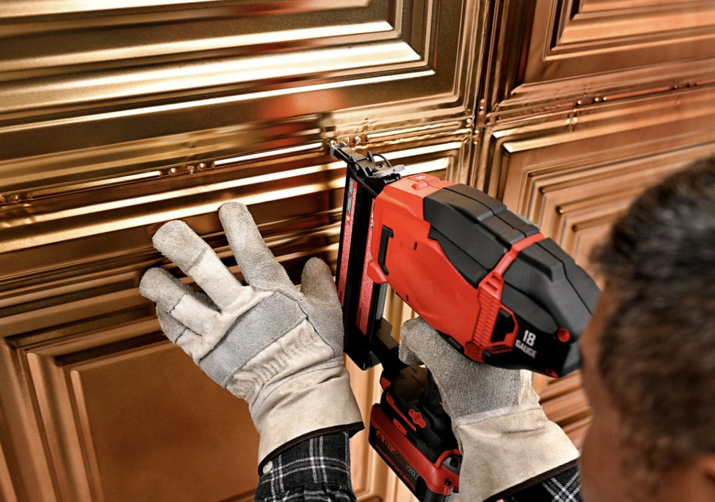 Nail up tin tiles being installed by a person on a ceiling.