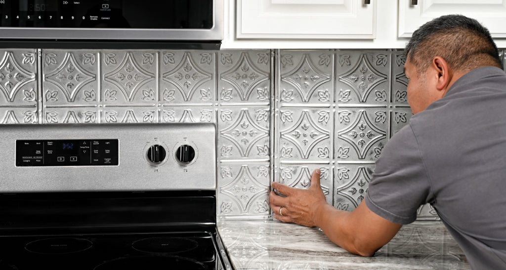 Snap lock tin tiles being installed by a man on a backsplash.