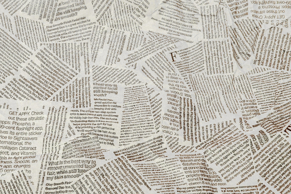 Close up of newsprint as wallpaper on a wall.