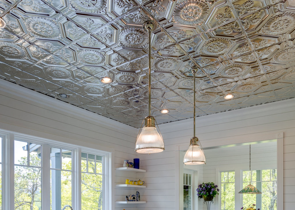 Close up of silver tin ceiling in a white kitchen with pendant lights.