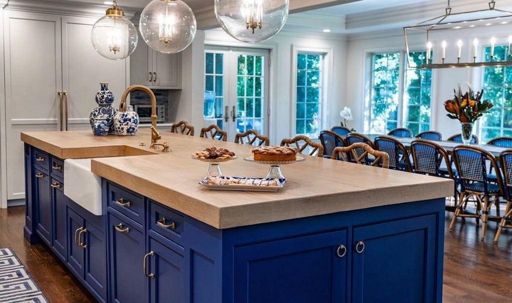 Blue kitchen island with butcherblock countertop and pendant lighting.