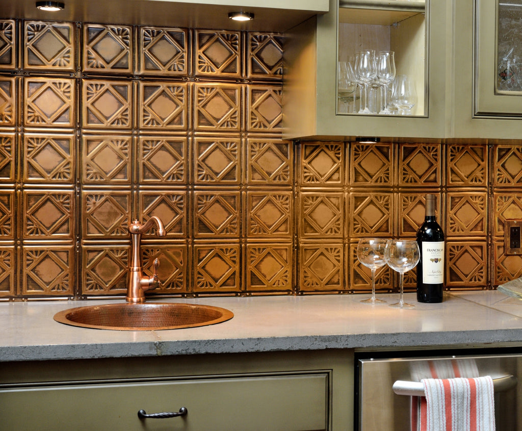 Tin tile backsplash in a copper color with green cabinets and copper sink.