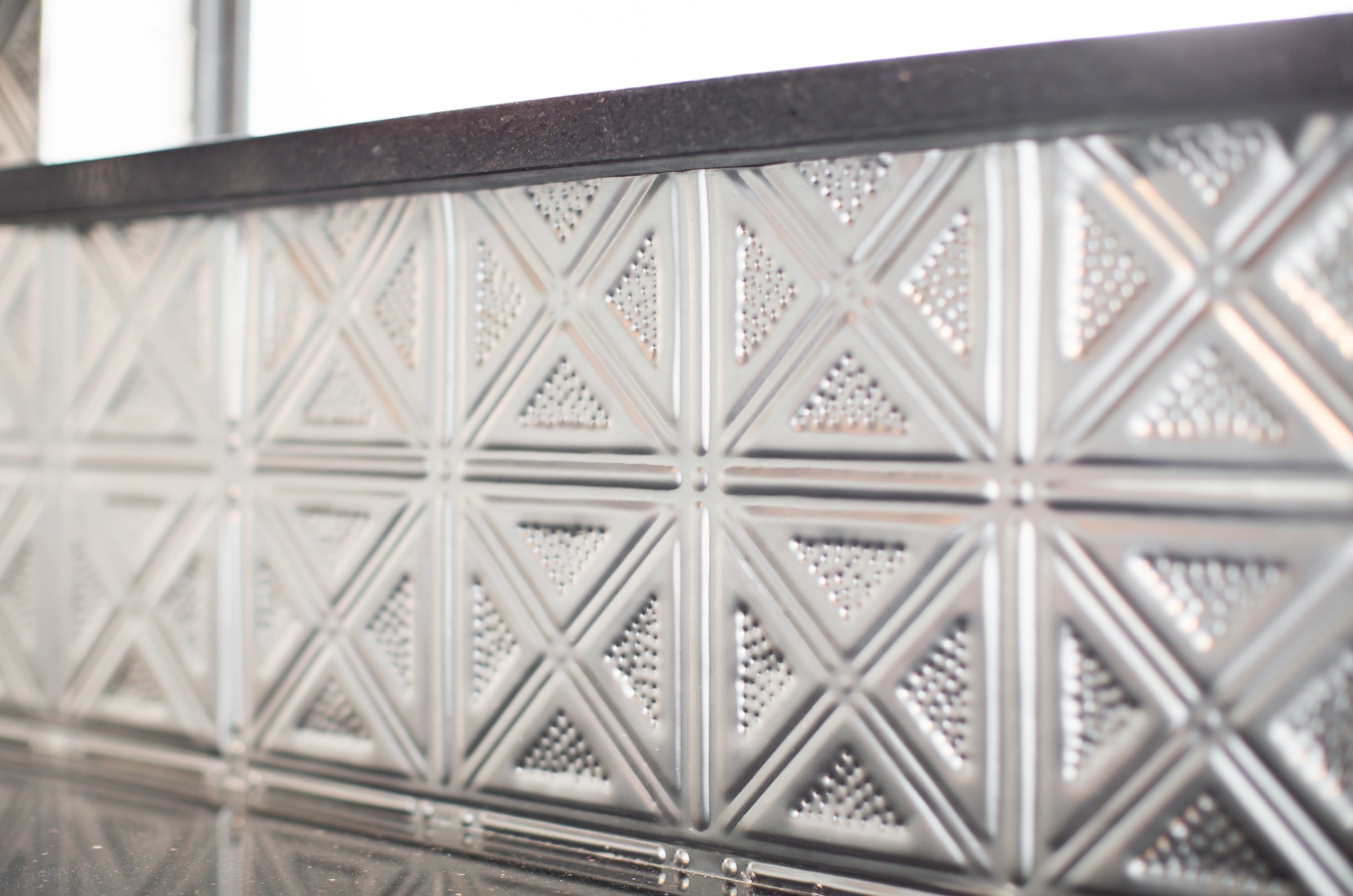 Close up of six inch tin tile on a backsplash.