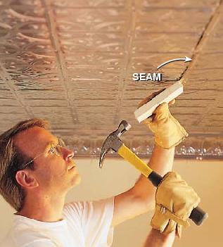 Person installing tin ceiling and working on the seam.