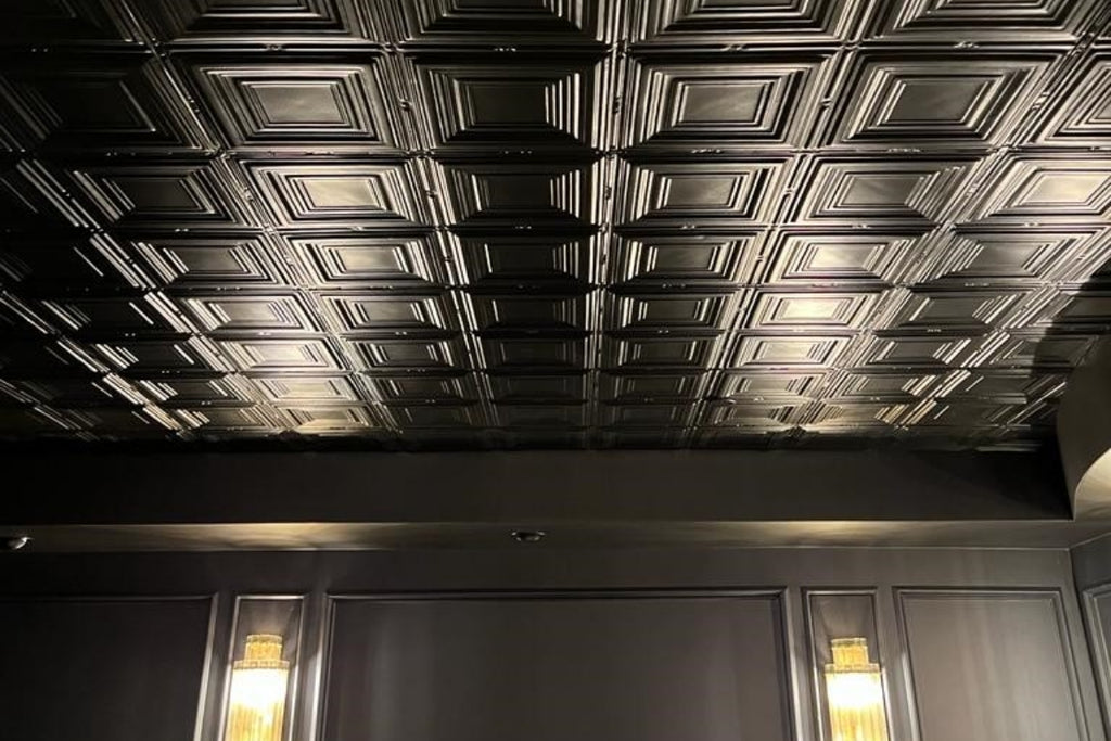 Black tin ceiling and sconces in a home theater room.