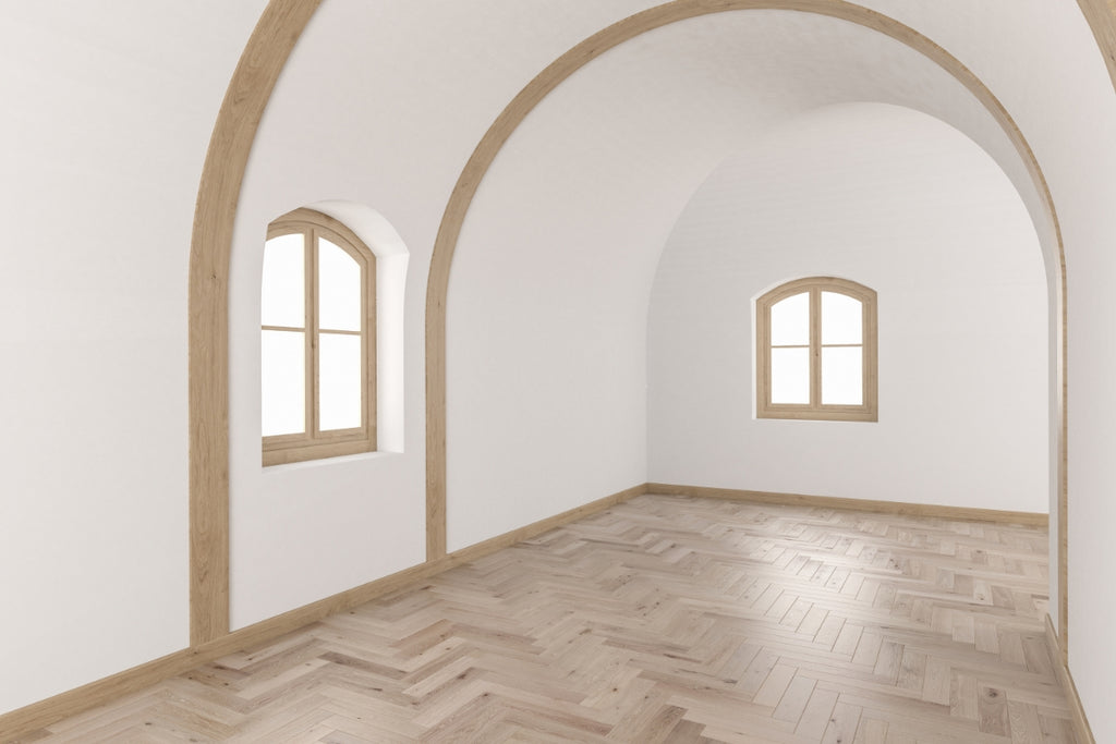 Empty room with curved ceilings and beams with light wood floors.