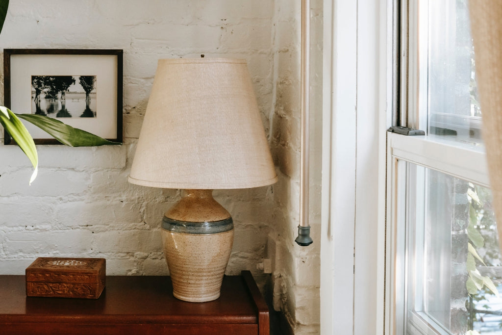 Corner of a room with window and lamp with distressed decor.