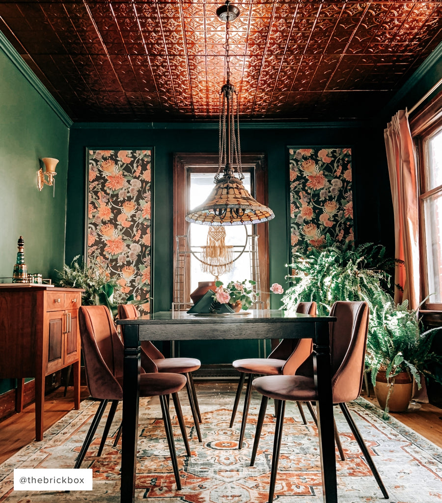 Dramatic dining room with lots of accents from colors to wallpaper and velvet dining chars.