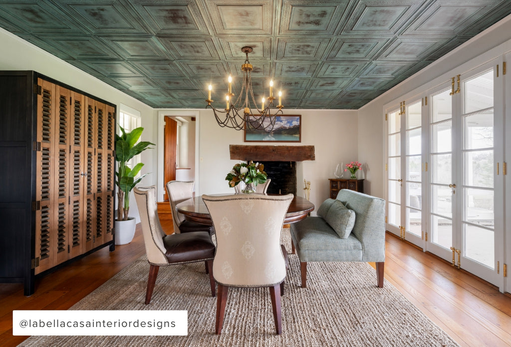 Large dining room with fireplace on one end, tin tile on the ceiling, and plush chairs.