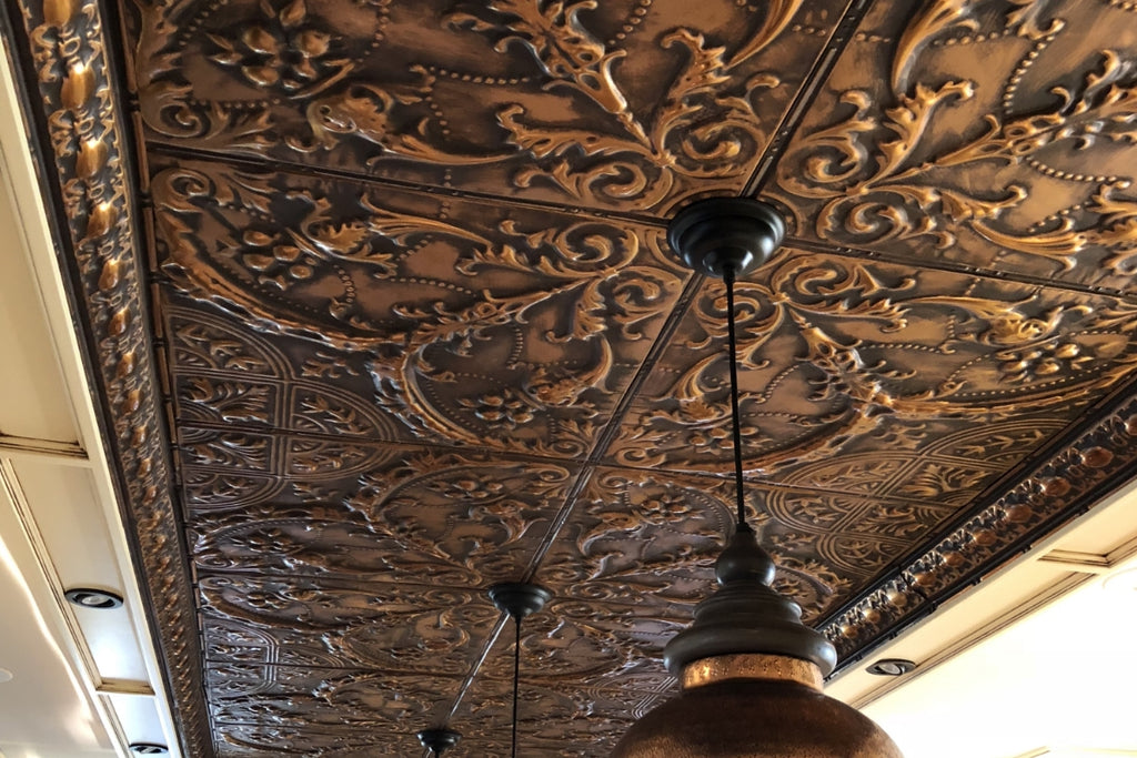 Large scale repeating pattern in bronze tin tile surrounding a pendant light.