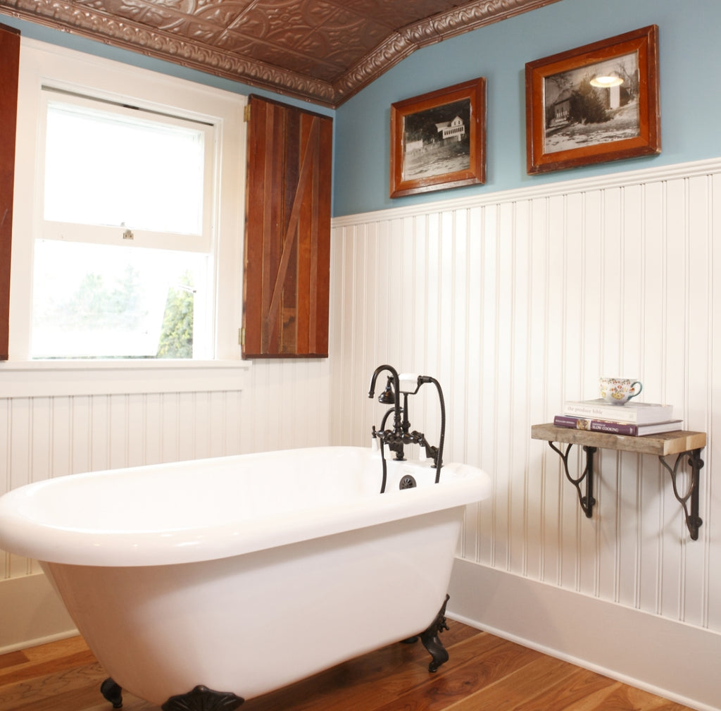 Clawfoot tub on a hardwood floor with white wainscot wall in the background.