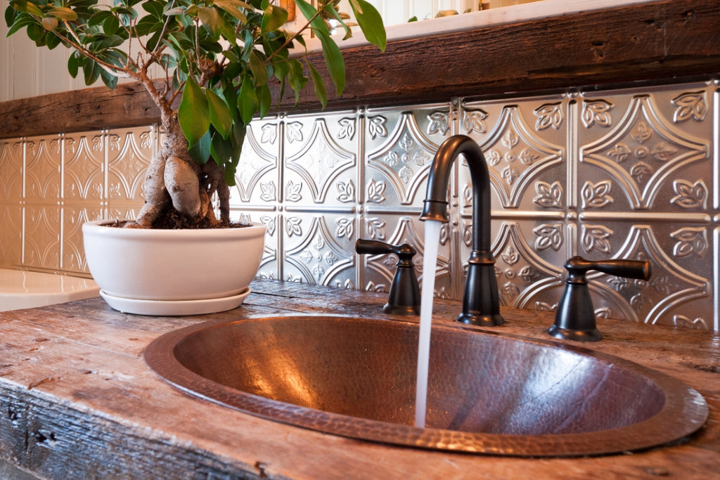 Bathroom sink with copper tin tile backsplash.