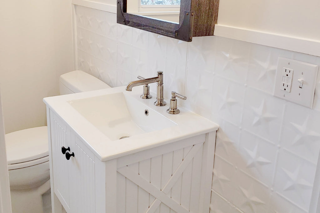 White bathroom with white tin tile backsplash behind the sink.