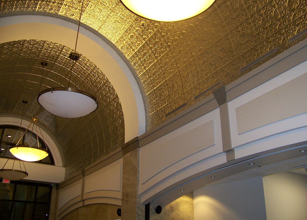 Barrel curved ceilings in a commercial space with gold tin tile coating them.