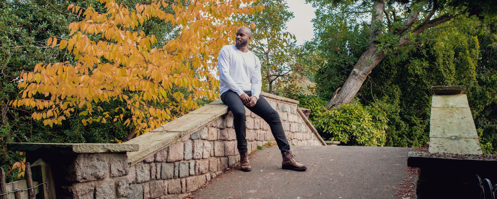 A tall athletic guy wearing a white XL tall long sleeve t-shirt on a bridge.