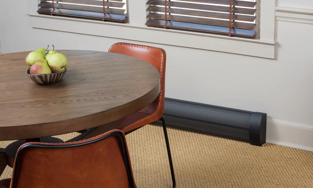 Black baseboard heat cover in a small dining room with round table and upholstered chairs.