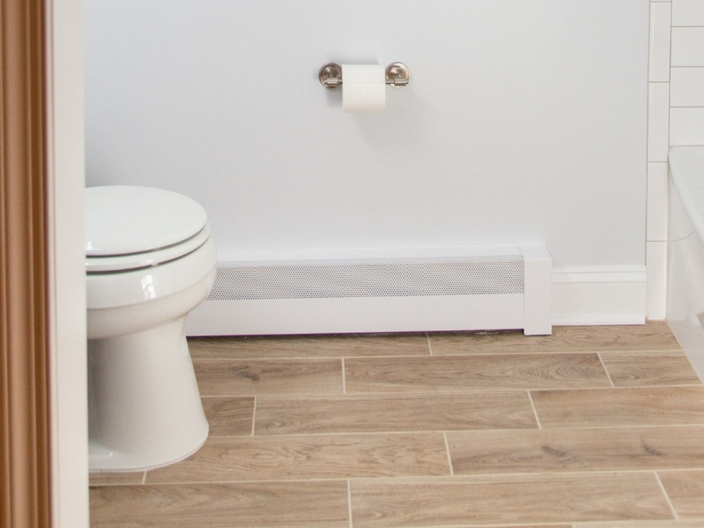 Bathroom with baseboard heater next to a white toilet with light wood look floors.