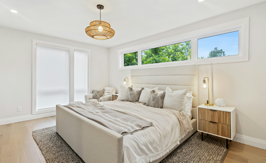 White bedroom with windows above the bed and rattan accents.