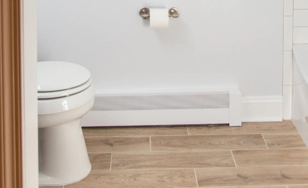 White baseboard heater in a bathroom with gray walls and white baseboard trim.