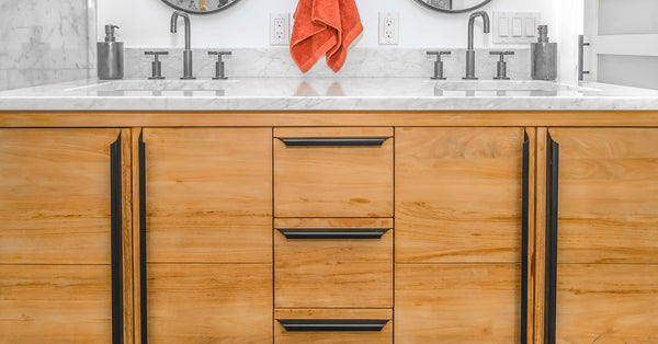 Dark cabinet hardware against light wood bathroom vanity.