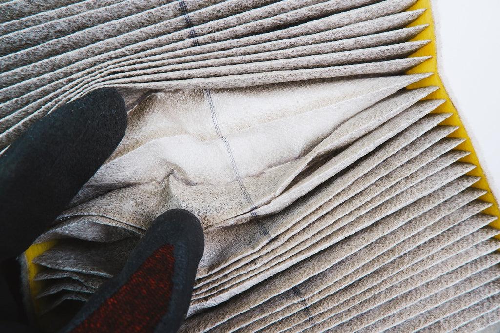 Dirty air filter being held by a gloved hand.