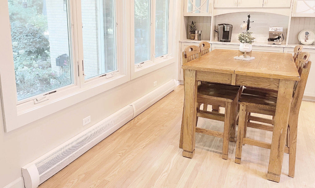 White baseboard heaters in a dining room with light wood floors and dining furniture.