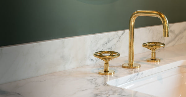 Gold bathroom faucet with marble countertops.