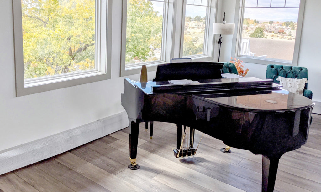 Living room with a black grand piano against windows and a white wall.