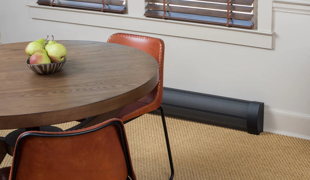 Small dining room with black hydronic baseboard heater and round table.