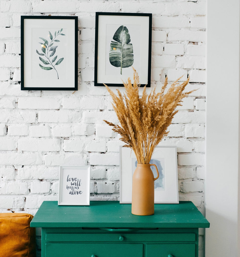 Brick wall in a bedroom behind a green dresser.