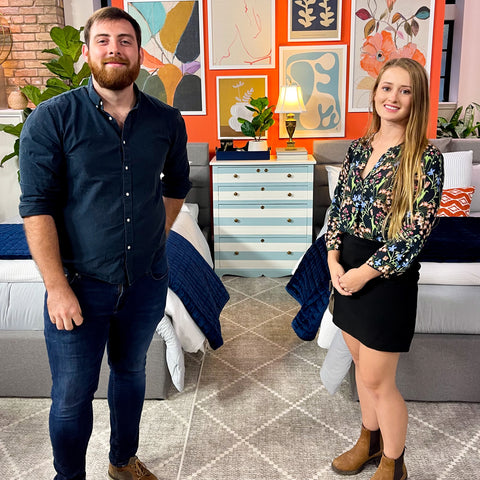 A photo of the founders of ARK Furniture Toronto in front of a striped dresser they refinished on the set of The Marilyn Denis show.